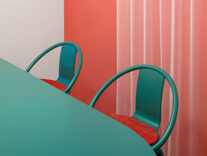 Farbkonzept Caf&eacute; Stuttgart: Gezielt eingesetzte T&uuml;rkis-Akzente auf Korallen-Hintergrund. Die abgerundete Formgebung der St&uuml;hle und Tische im Gastro-Ladenbau schafft ein einladendes und verspieltes Ambiente